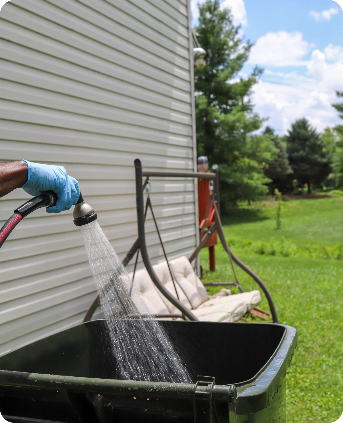 Person watering outdoor garden bin