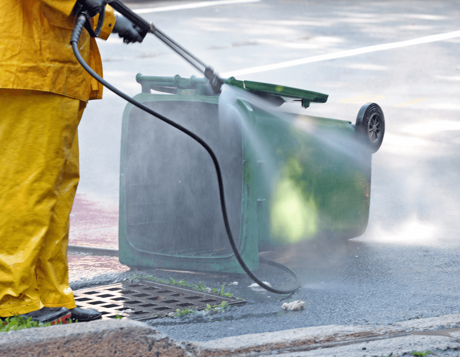 Sanitation worker washing overturned trash bin